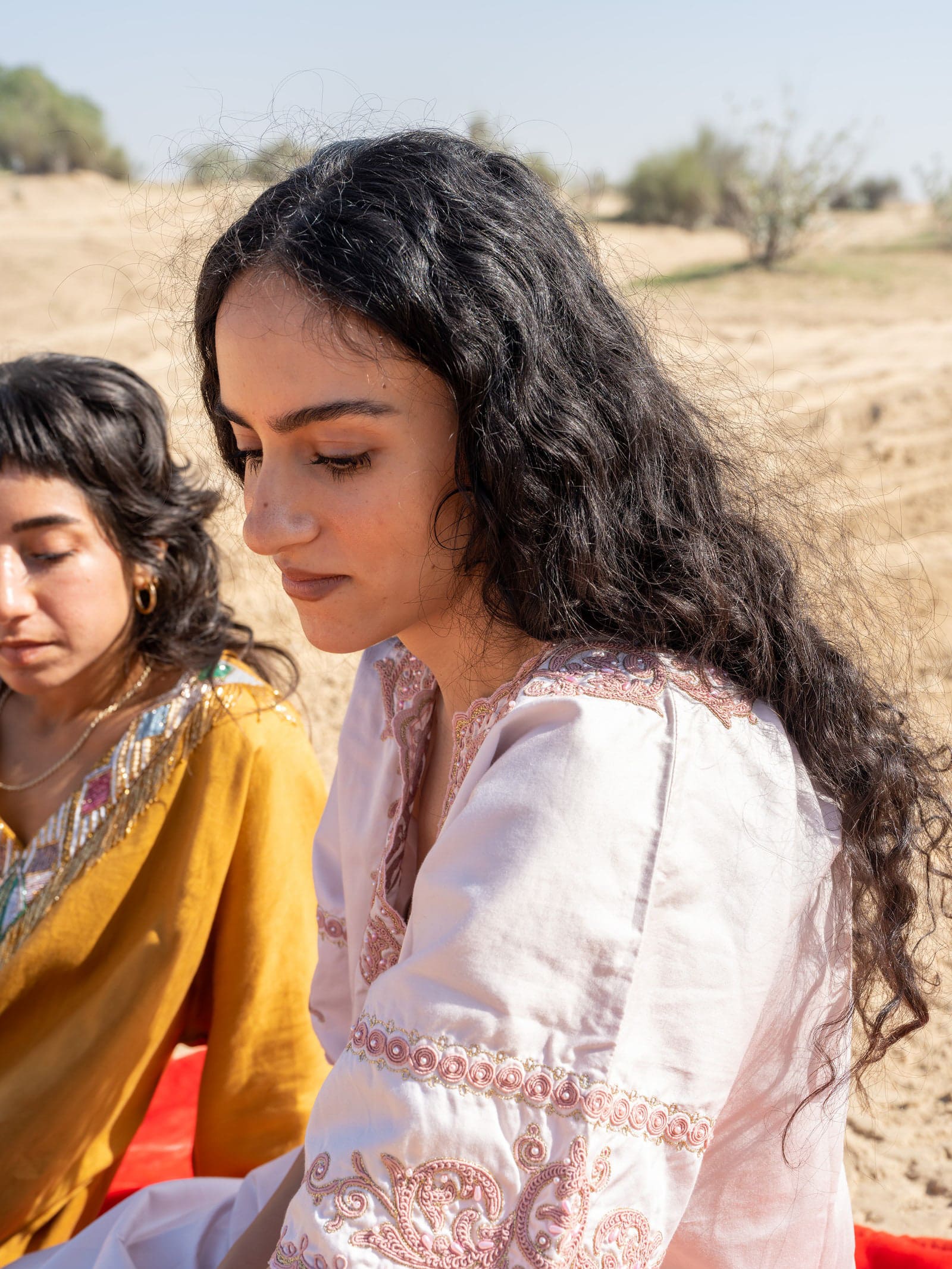 Nouri sits still as Azra emblazons her hand with henna while Zahra looks on appreciatively