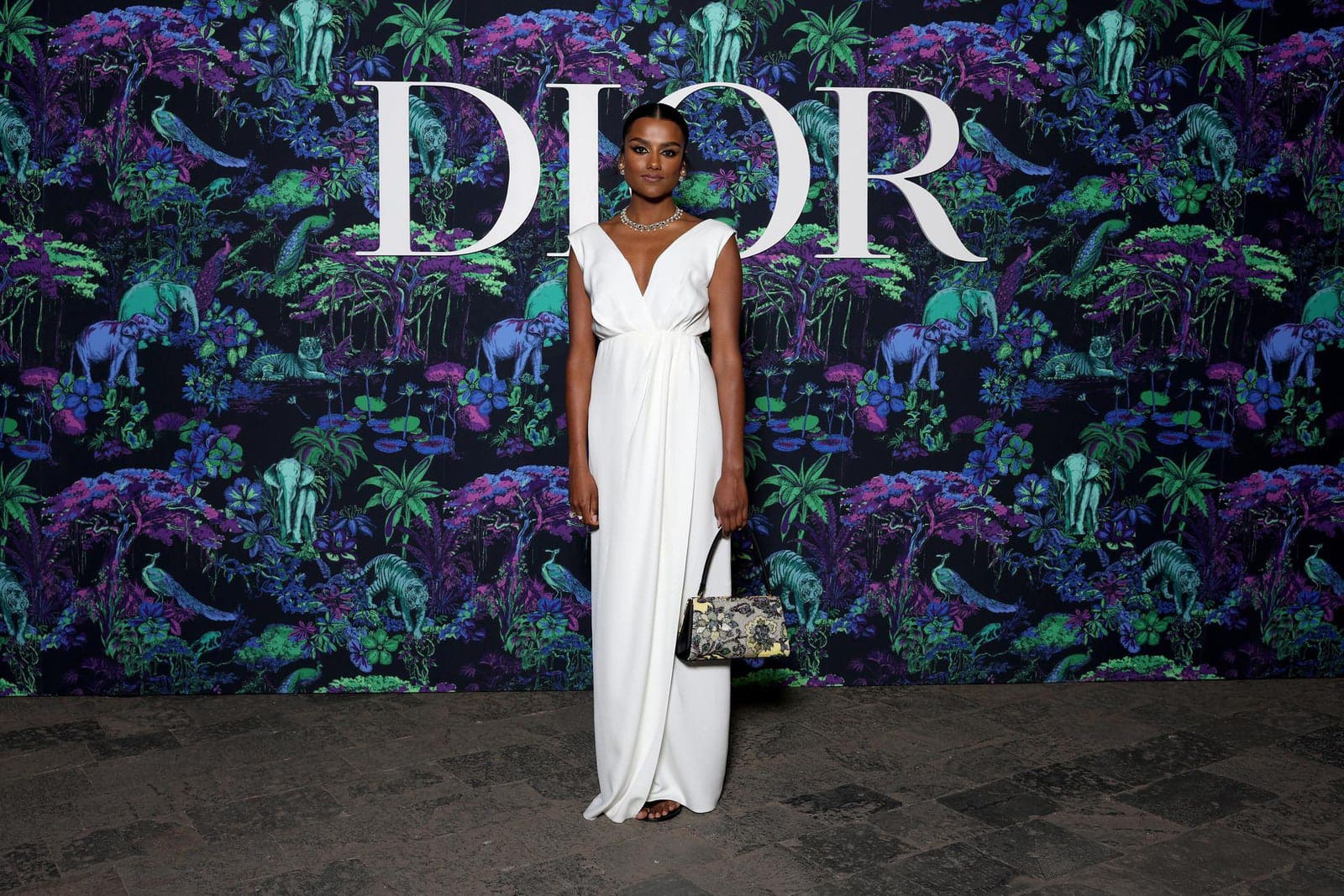 Dior Fall/Winter 2023 Show In Mumbai Simone Ashley wore a Dior Pre Fall 2023 white silk dress with a Dior bag and shoes.