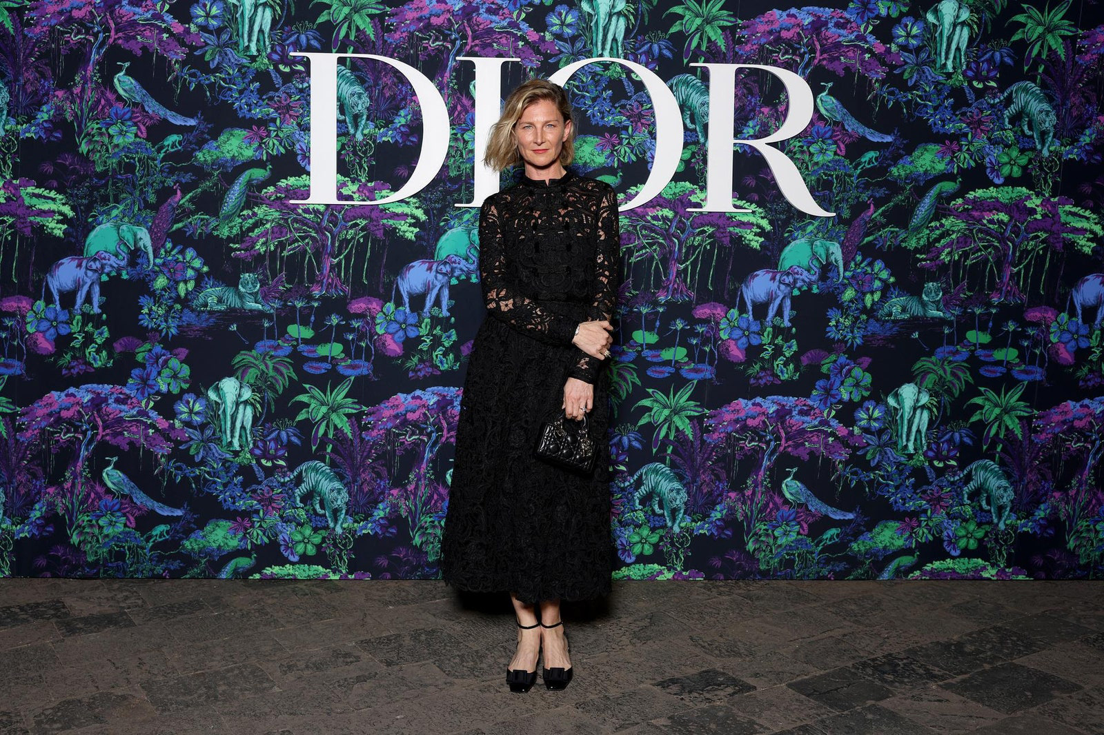 Dior Fall/Winter 2023 Show In Mumbai Elizabeth Von Guttman wore a Dior Spring-Summer black embroidered lace dress with a Dior bag and shoes.