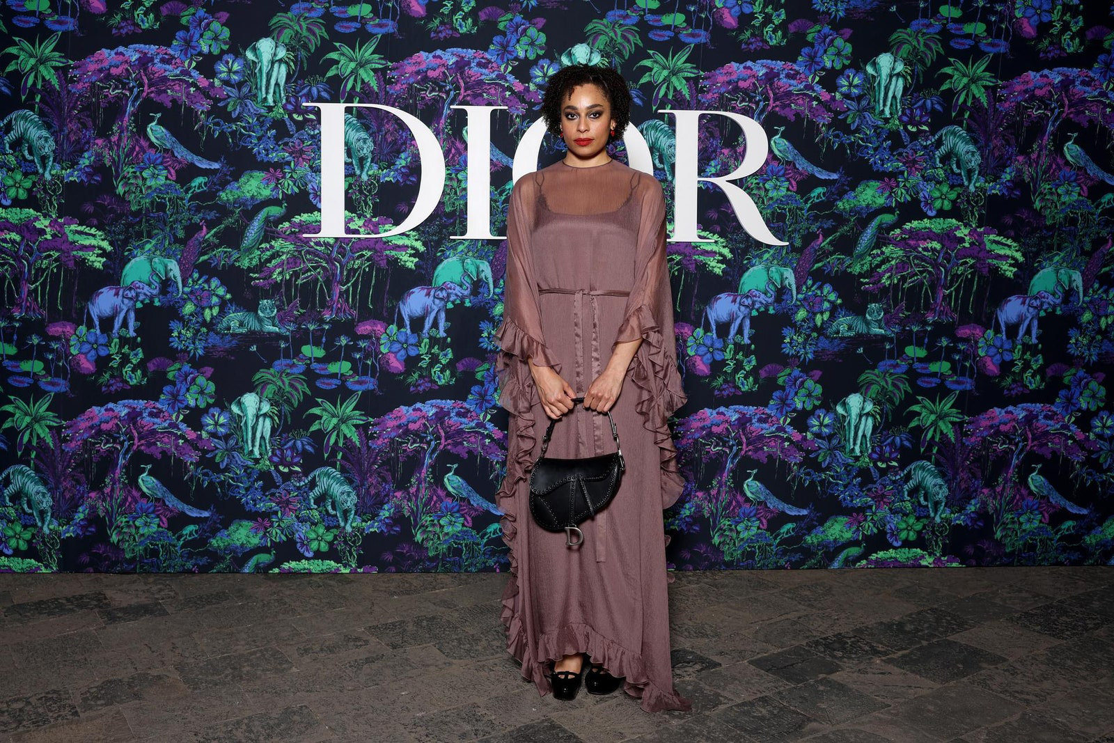 Dior Fall/Winter 2023 Show In Mumbai Celeste Epiphany Waite wore a Dior pink silk dress with a Dior bag and shoes.