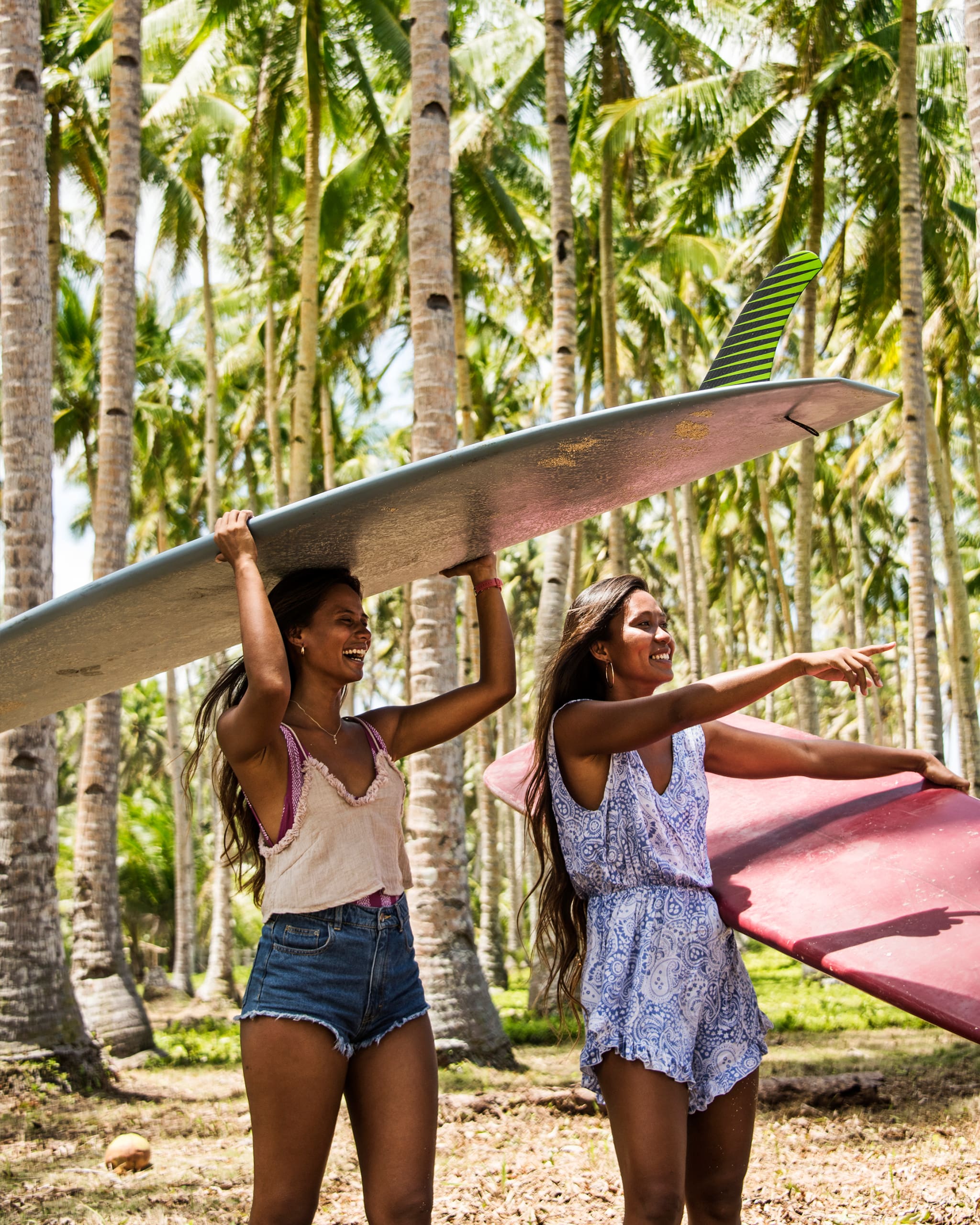 Ikit Agudo and Aping Agudo holding surfboards while walking in Siargao