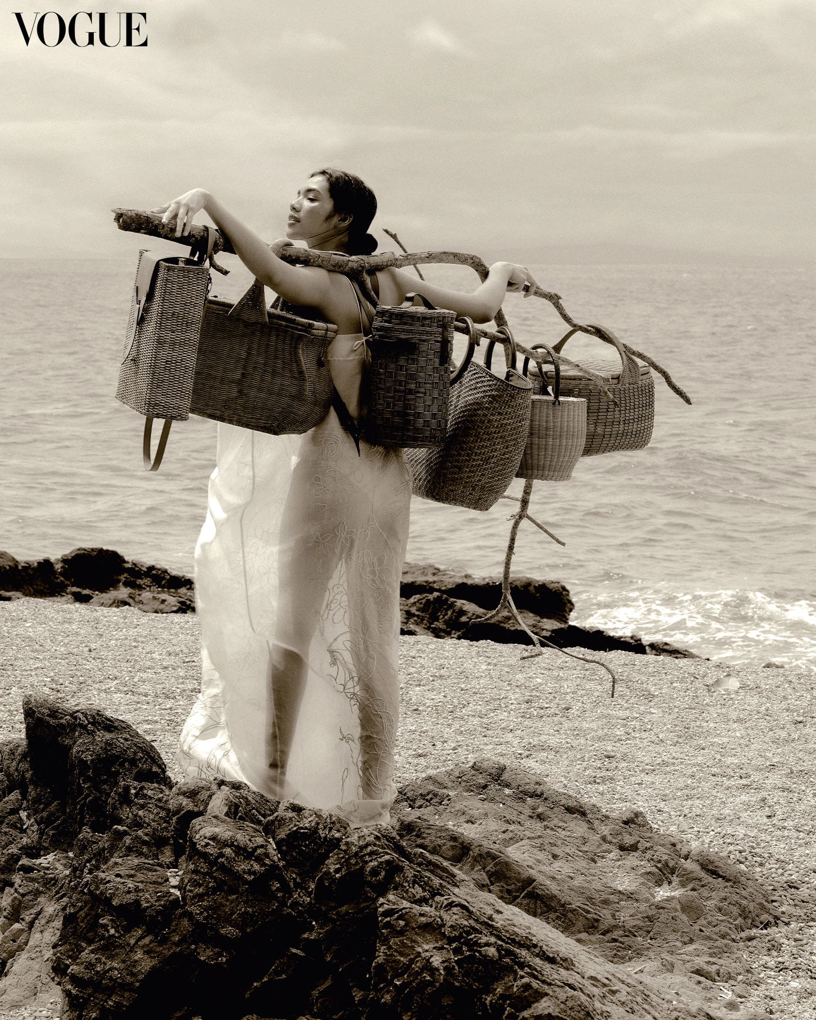 Filipina woman wearing a dress at the beach holding a branch with Batangas woven bags and baskets