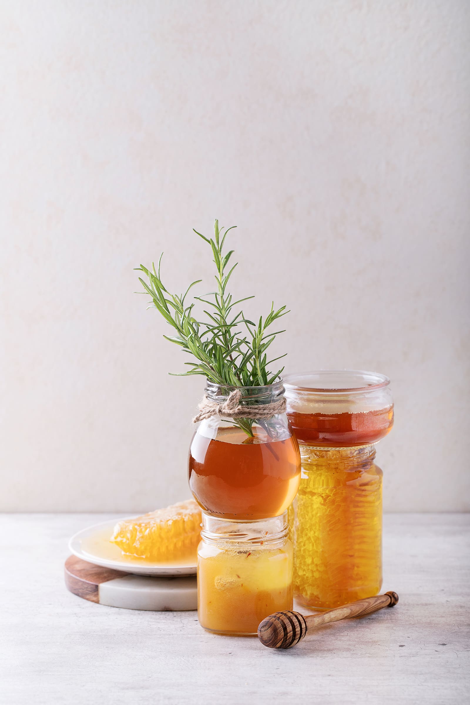 Ayurvedic ingredients Honey in jar with honey dipper and honeycomb over white background.