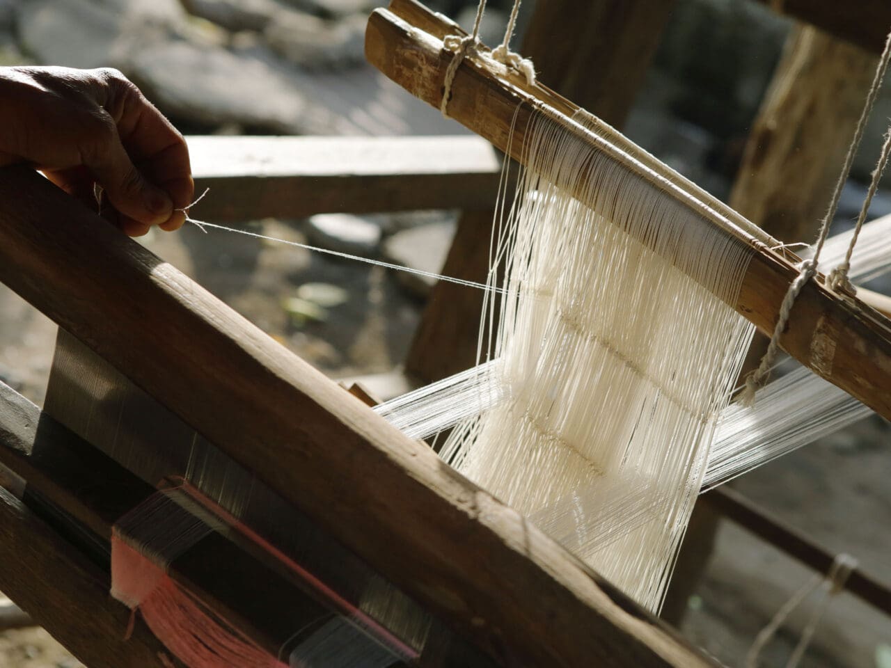 A weaver setting up a traditional floor loom
