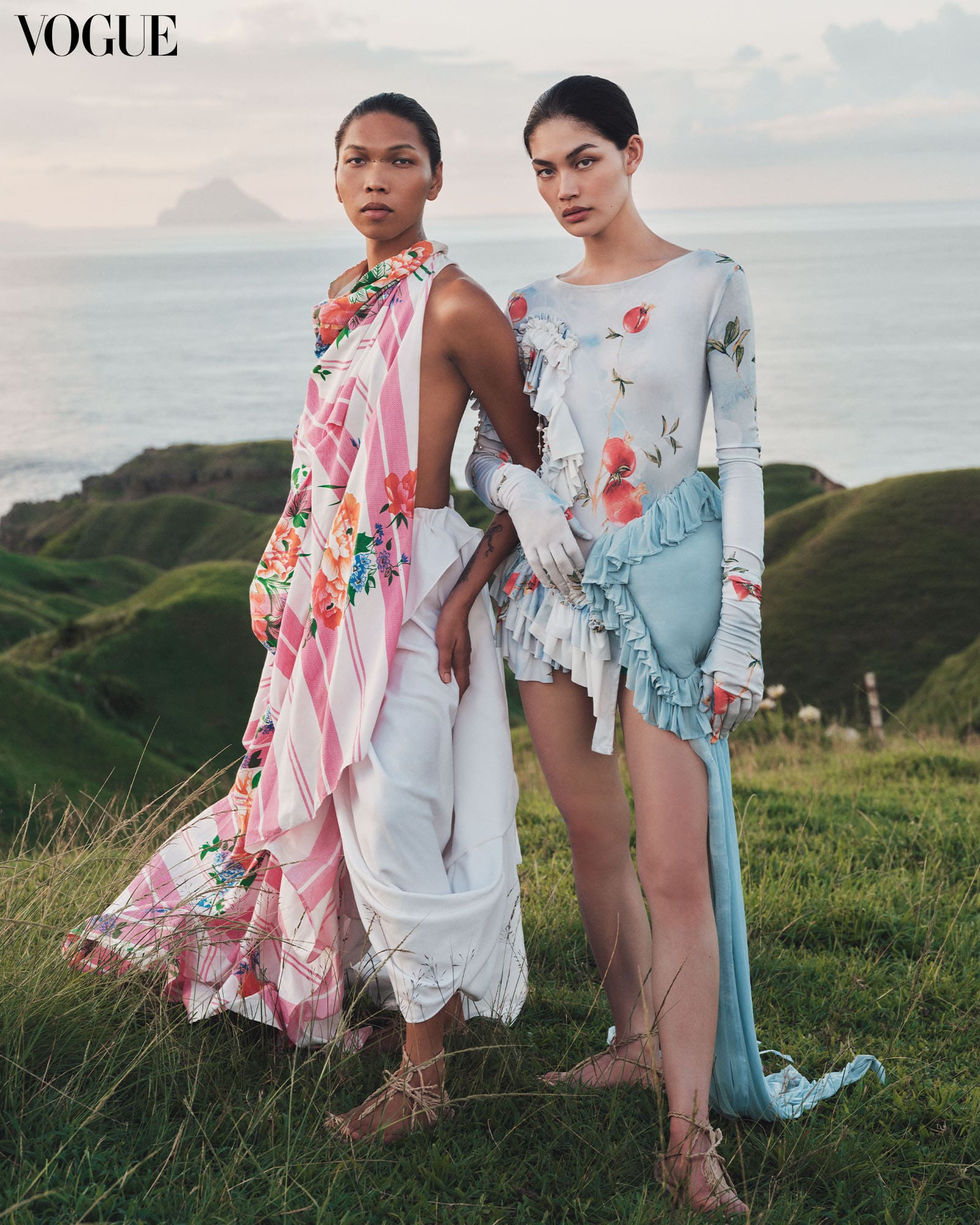 Rina wears a ZIXUAN LIU Bedding-Inspired Dress, a fusion of playful ruffles, layered textures, and a vintage fruit print. Lukresia wears a JUDE MACASINAG knotted wrap skirt made of Sparrow kumot worn as a top and a crepe free-draped skirt. Both wear Ivatan Tukap rope sandals.