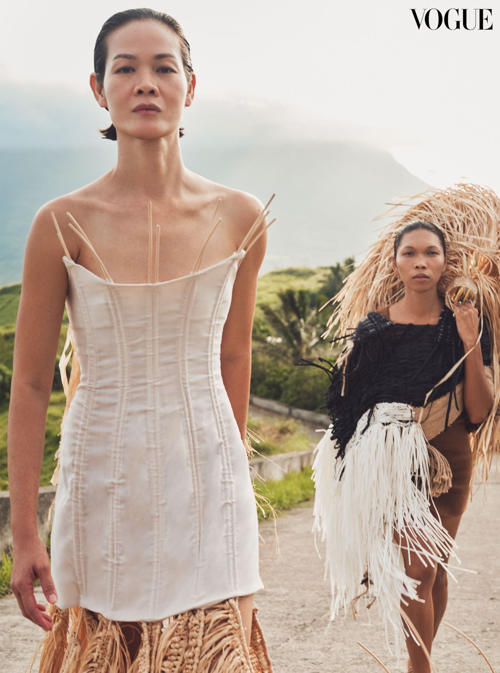 Jo Ann wears the Tree Altar Look by RACHEL MIN LEE, featuring a corset dress embellished with raffia weavings. Lukresia wears the Weaver Look by RACHEL MIN LEE, which embraces the art of handwoven looms and deconstructed silhouettes.