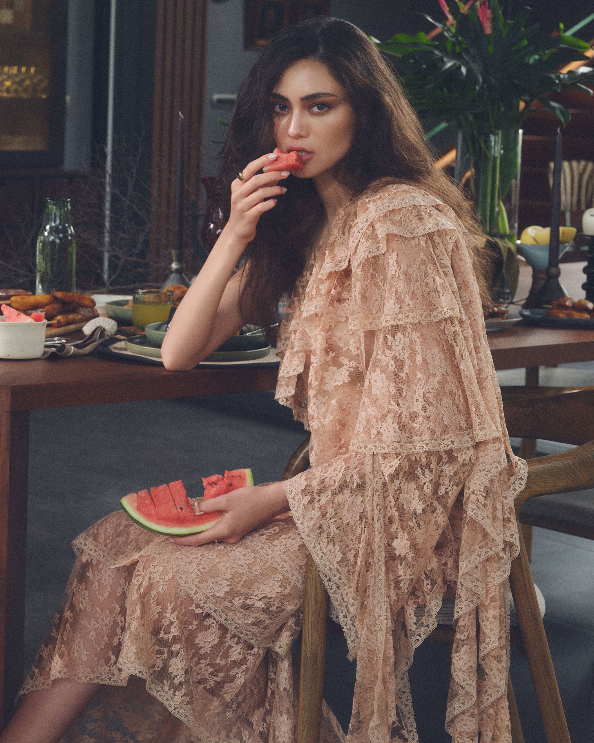 a girl wearing a lacy peach dress while eating watermelon