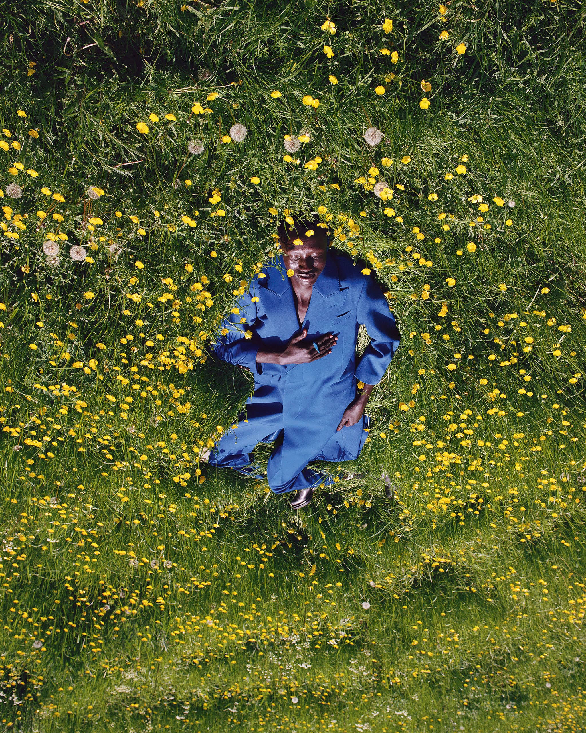 A model wearing a blue outfit on the green grass with yellow flowers