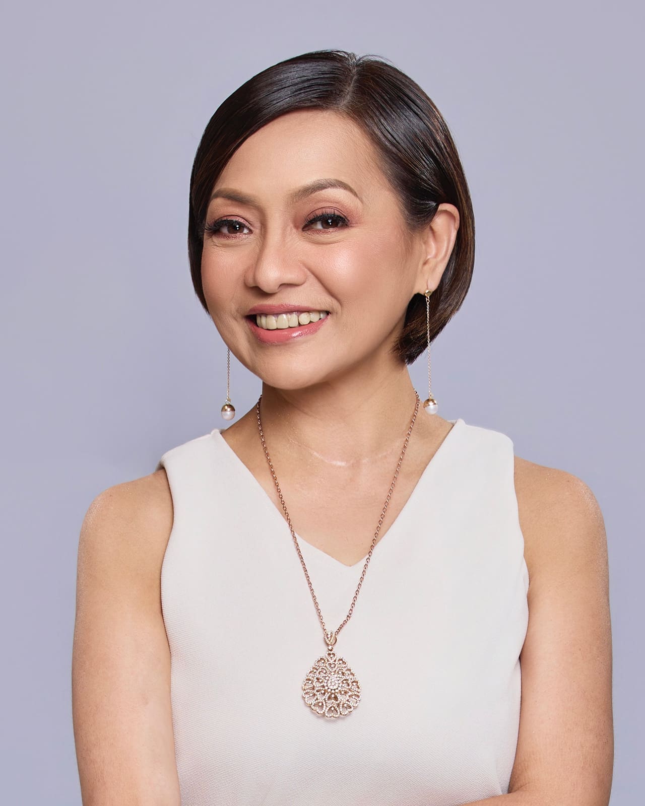 Chemist Pinky Tobiano wearing white ensembles against a gray background