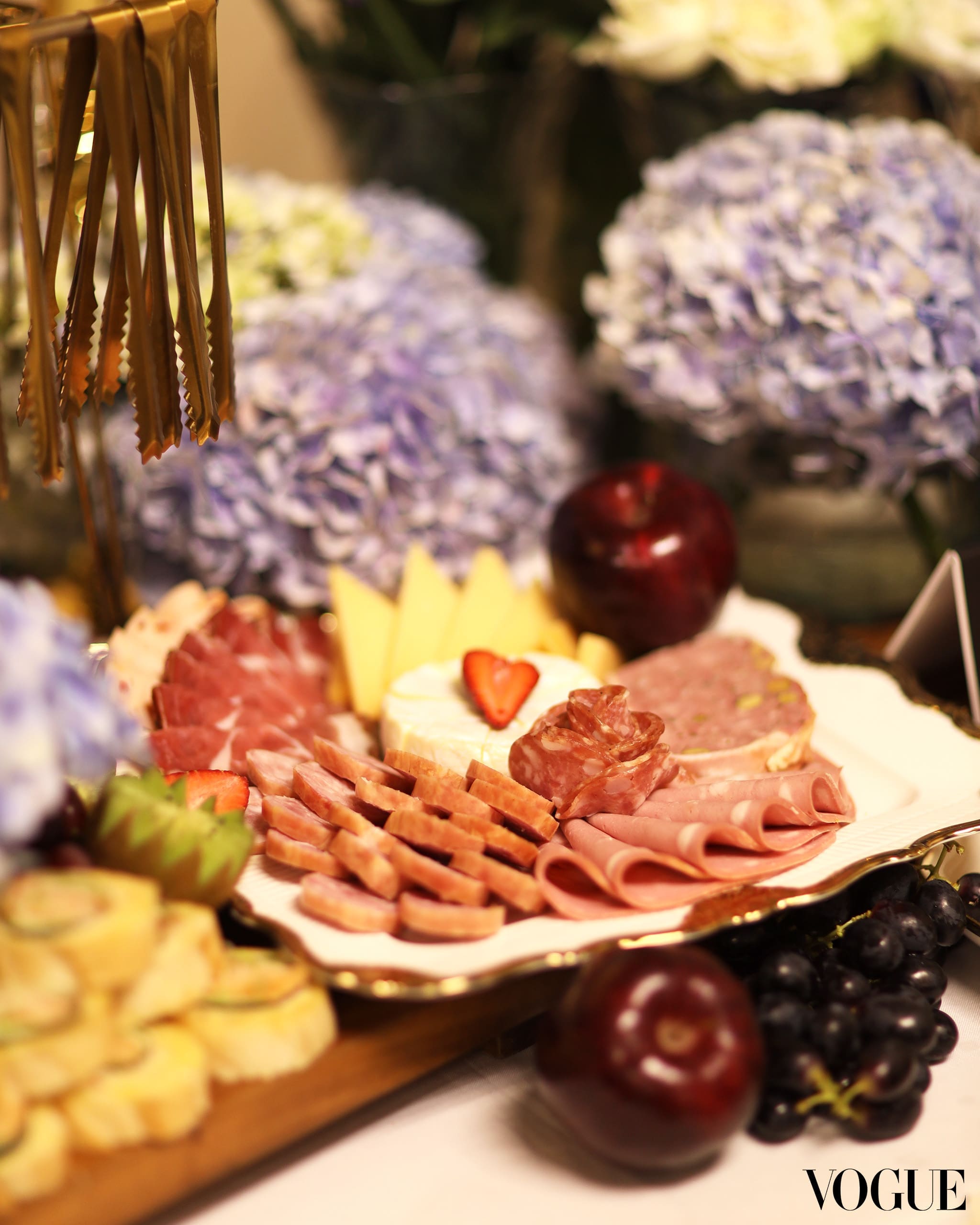 Goodness Graze’s table with assorted charcuterie, cheeses, and fruits, surrounded by fresh flowers. Photo by Ed Simon.