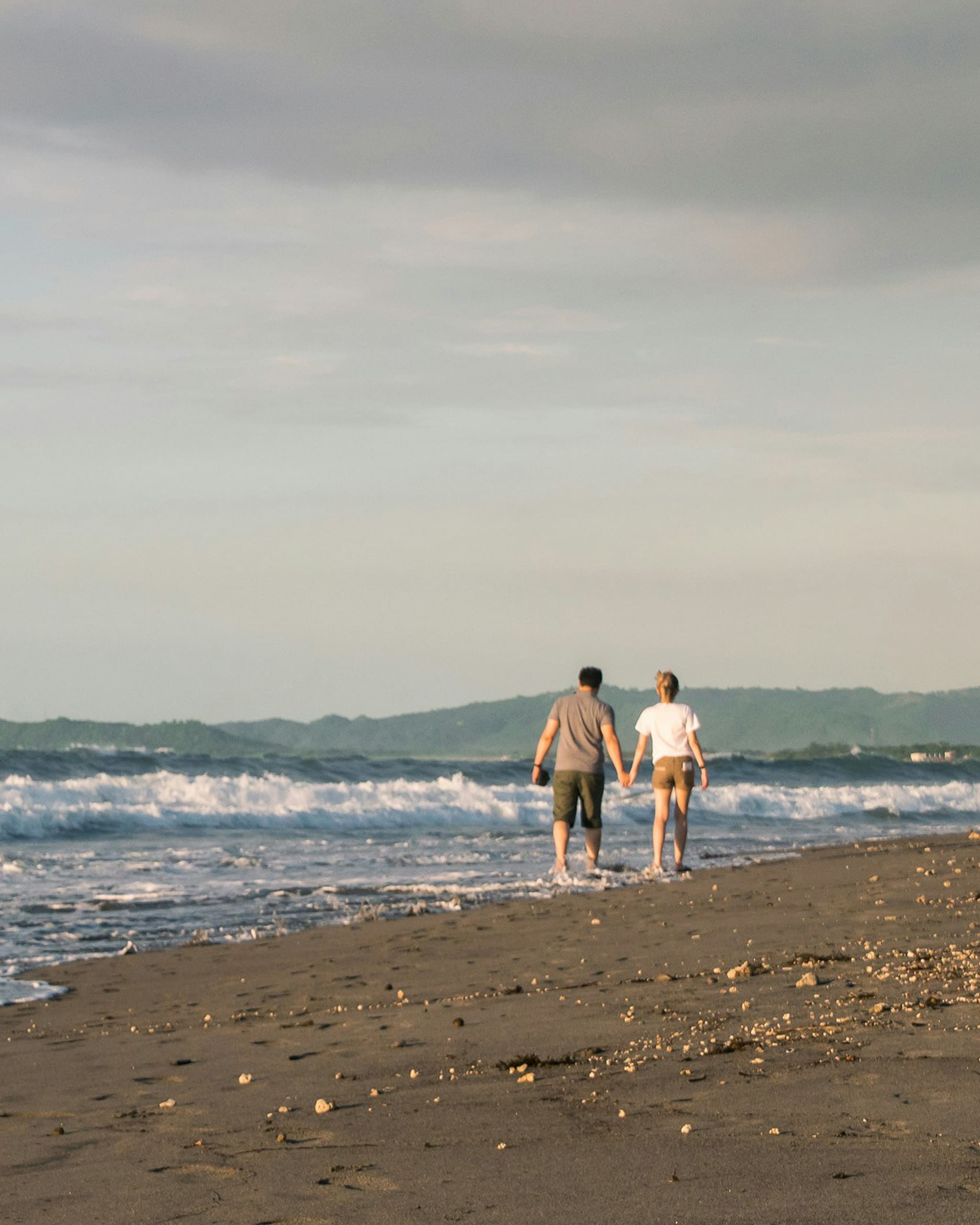 photo of a couple holding hands walking on the beach by vernon raineil cenzon | vogue philippines