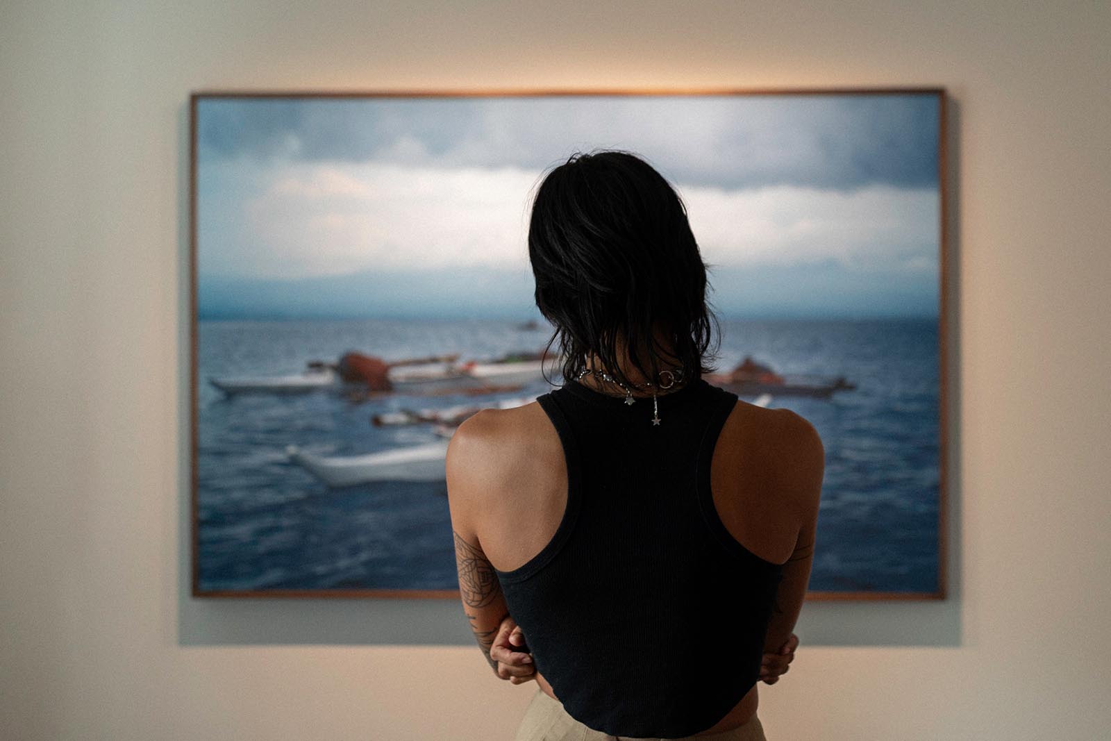 Picture of a person with their back turned, viewing one of Hannah Reyes Morales's photo on display.