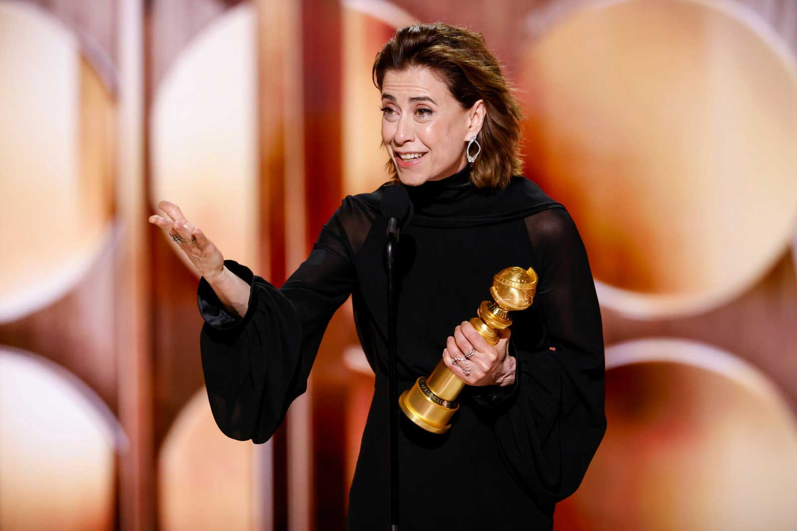 Actress Fernanda Torres holding her Golden Globe while delivering a speech onstage after winning the award for her role in 