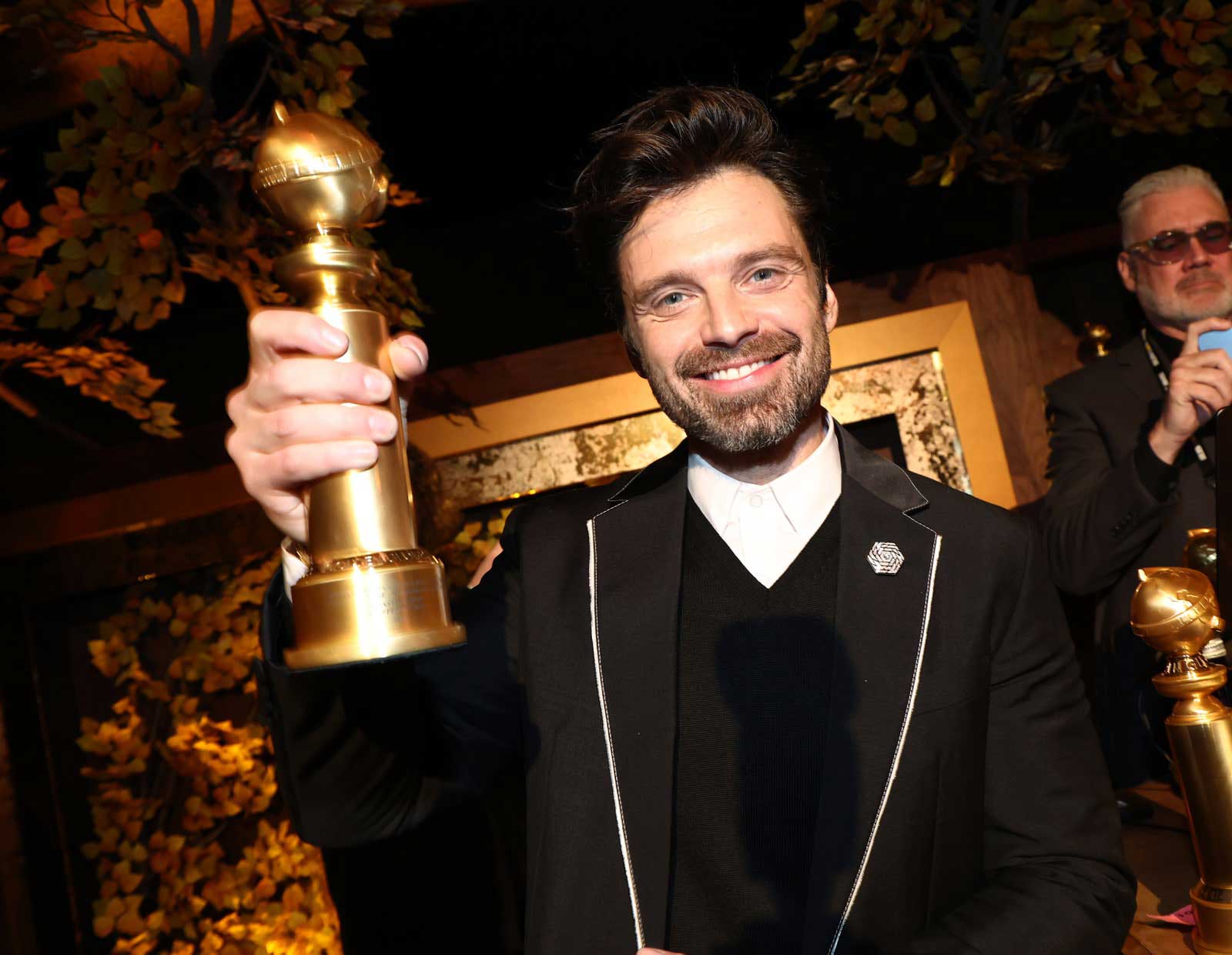 Actor Sebastian Stan holding his Golden Globe up which he won for 