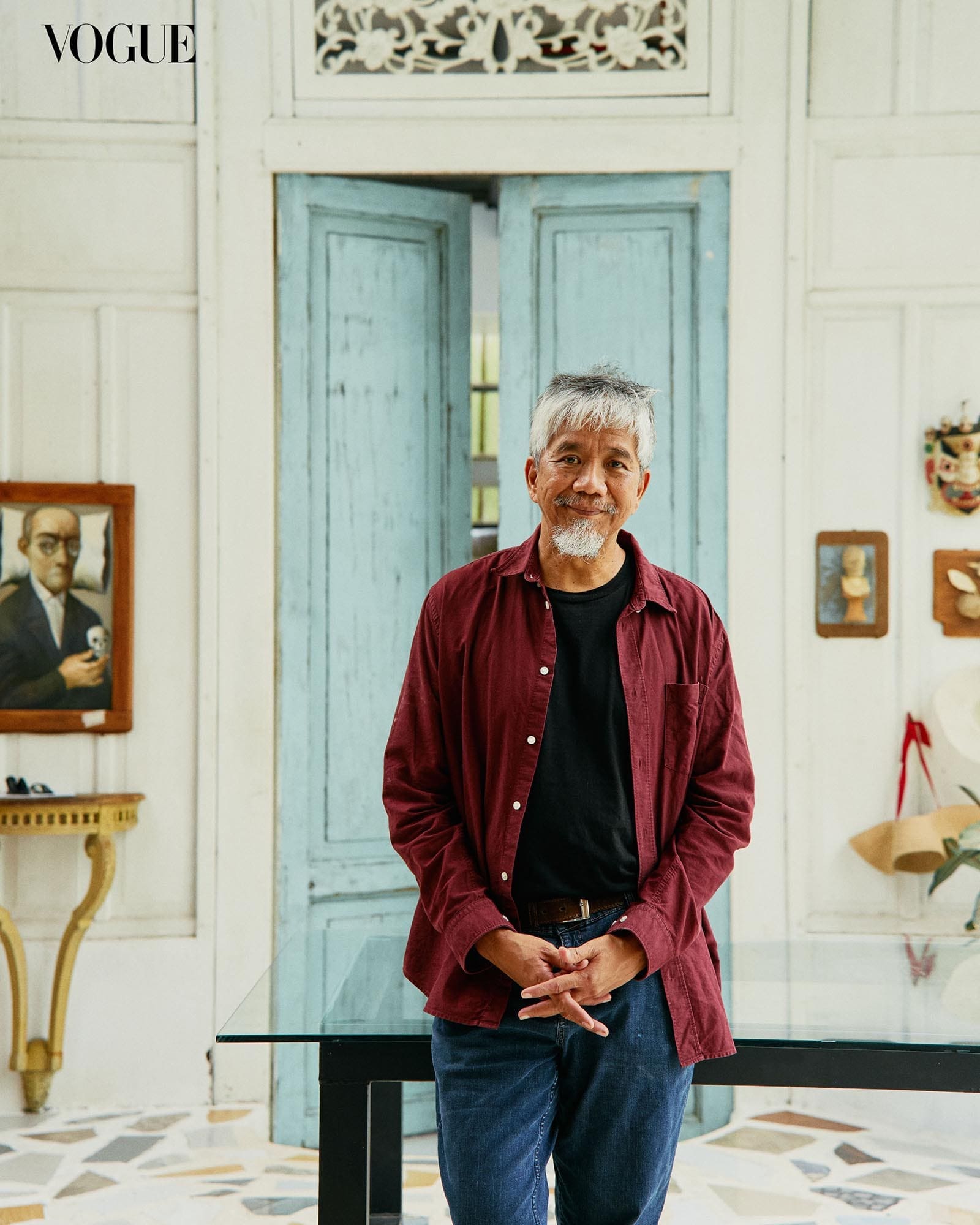 A wide photograph of Manny Garibay wearing a red polo, rested against a glass dining table.