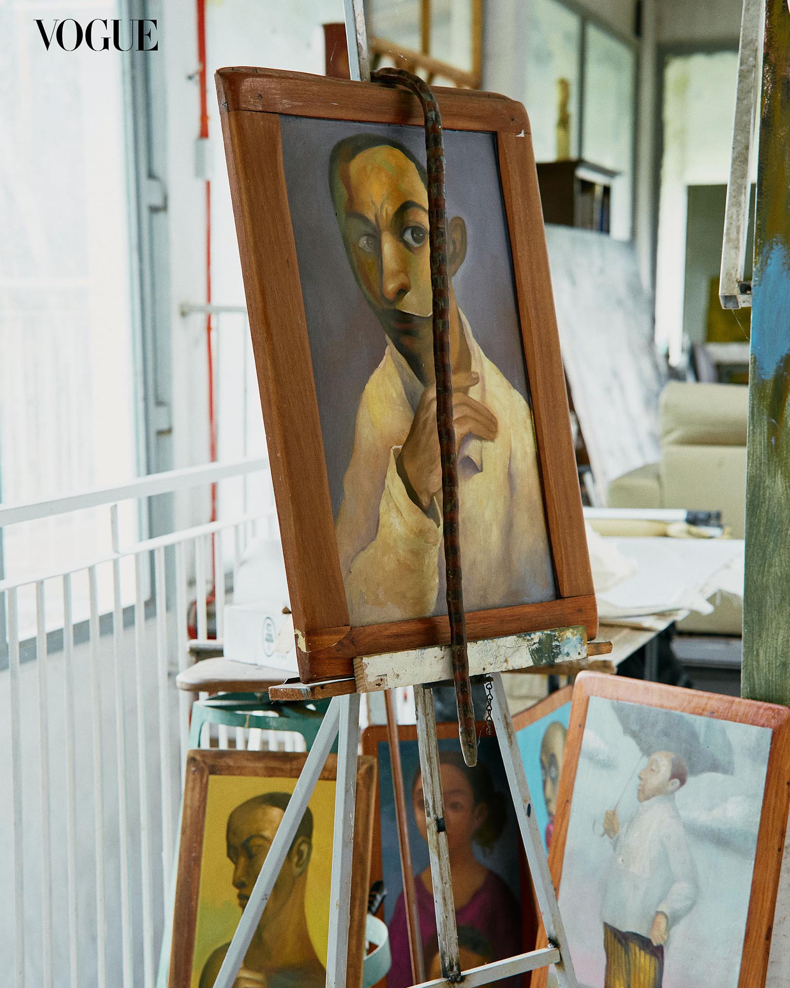 Photograph of a painting on an easel, with paintings all around it.