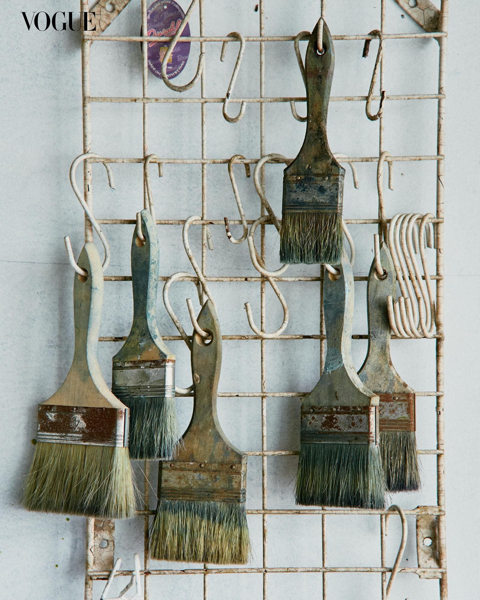 Closeup photo of paintbrushes hanging on a wall.