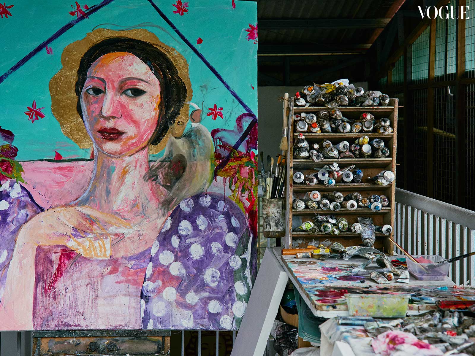 Photo of a studio space, with shelves of paint and a woman painted on canvas.